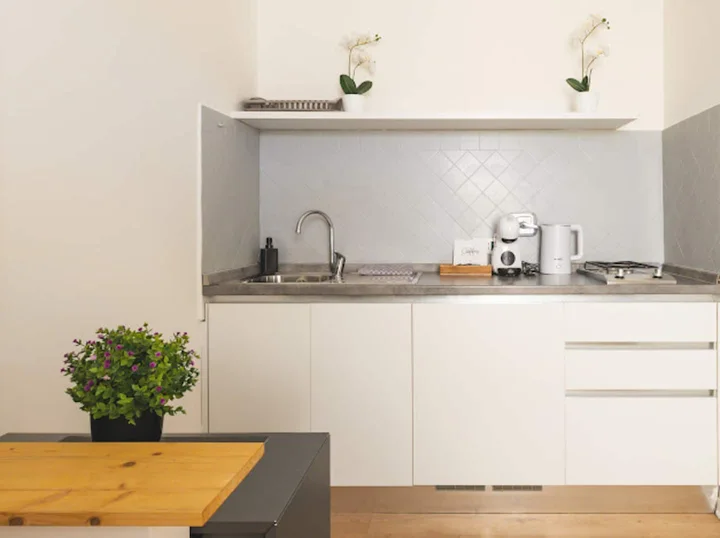 Angolo cucina bianco con piano di lavoro e piccolo tavolo in legno